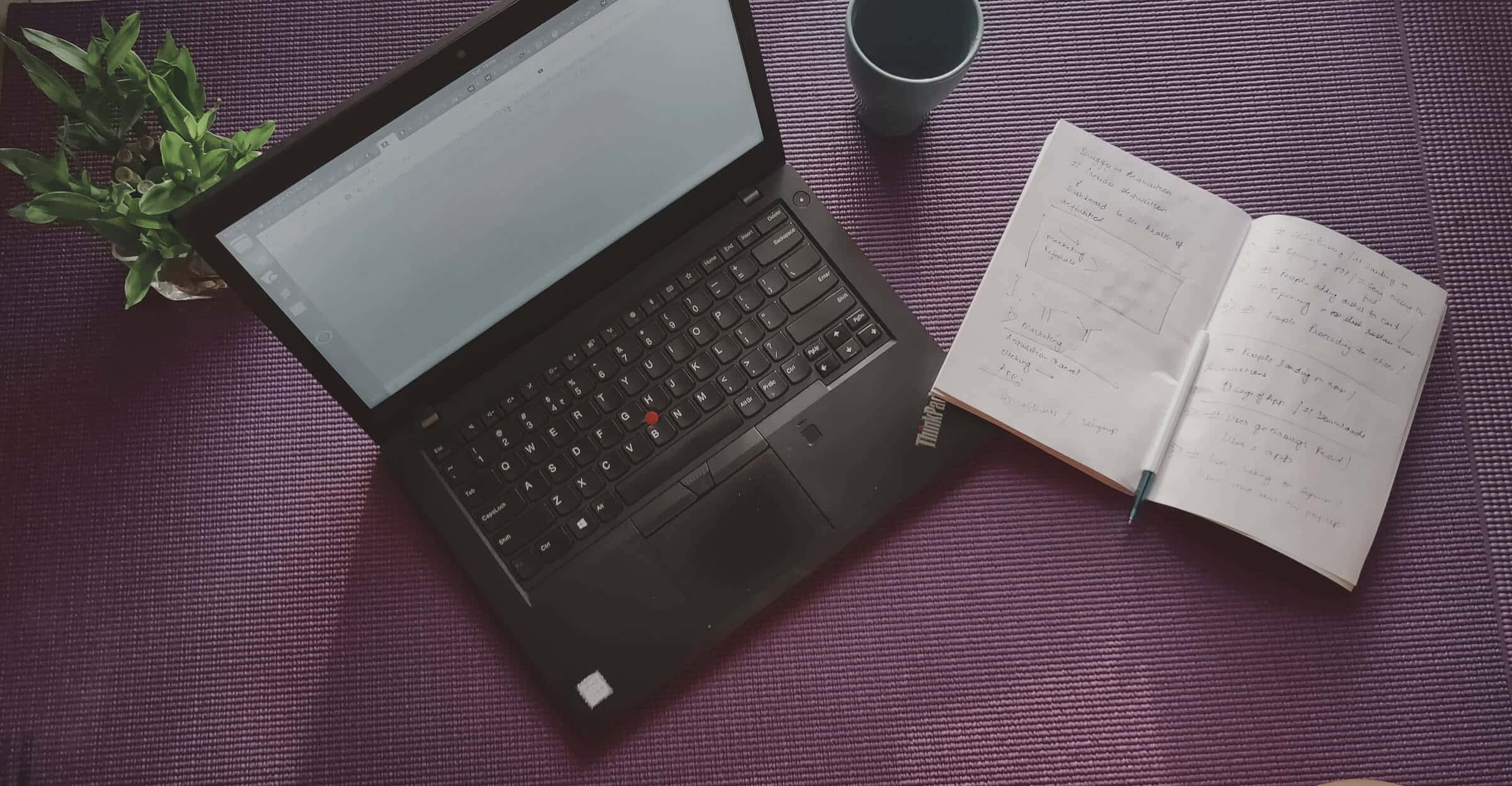 vista superior de una laptop y un cuaderno que se encuentran sobre una mesa